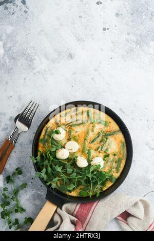 Omelett mit Spinat, grünen Bohnen, Kartoffeln und Spinat gesunde Lebensmittel in schwarzer Bratpfanne auf grauem Stein alten rustikalen Hintergrund. Traditionelle Frittata für Br Stockfoto