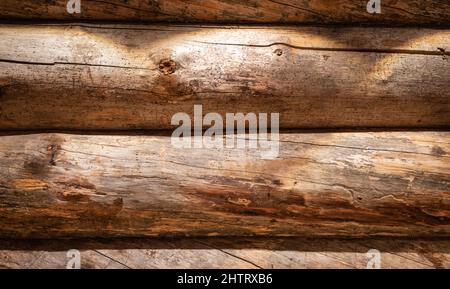 Holzwand aus horizontal verwitterten Stämmen. Hintergrund mit Holzstruktur und Spotlight. Stockfoto