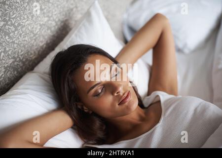 Den Tag verschwingen. Eine schöne junge Frau, die in ihrem Bett schläft. Stockfoto
