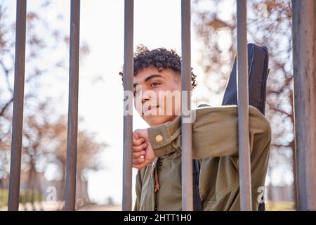 Lateinischer lächelnder Mann hinter dem Zaun Stockfoto