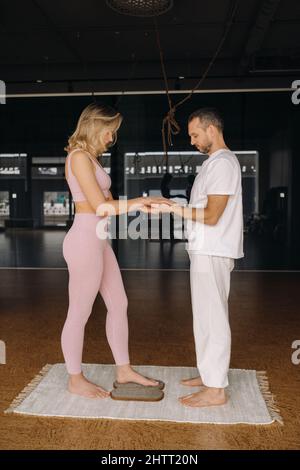 Ein Mann und eine Frau machen Yoga auf Brettern mit Nägeln im Fitnessstudio. Stockfoto