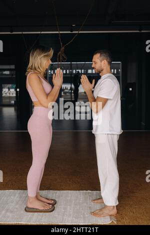 Ein Mann und eine Frau machen Yoga auf Brettern mit Nägeln im Fitnessstudio. Stockfoto