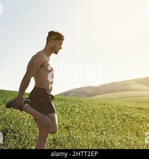 Streckt seine Quads. Kurzer Schuss eines jungen Mannes, der sich vor einem Lauf im Freien dehnt. Stockfoto