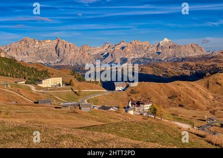 Luftaufnahme auf dem Grödner Pass mit Gebäuden auf der Spitze, Gipfeln und Felswänden der Dolomitenberge rund um den Falzarego Pass in der Ferne. Stockfoto