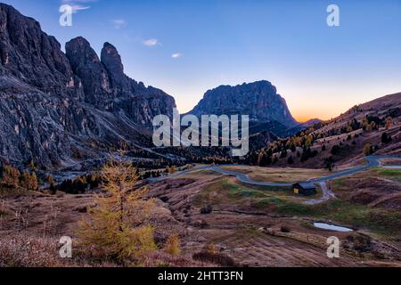 Nach Sonnenuntergang über der Sellagruppe (links) und der Langkofelgruppe in der Ferne führt eine kurvenreiche Straße hinauf zum Grödner Pass. Stockfoto