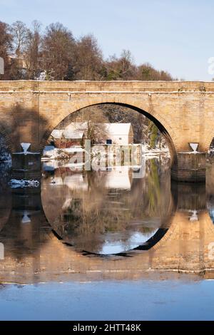 Die alte Maismühle, eingerahmt von einer vorbiegeten Brücke über den Fluss Wear, in Durham City, England, Großbritannien Stockfoto