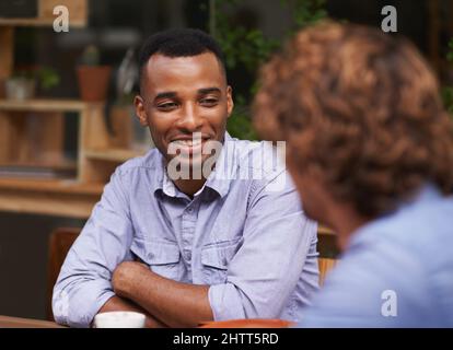 Ich hole einen alten Freund ein. Ein hübscher junger Mann, der mit einem Freund in einem Café sitzt. Stockfoto