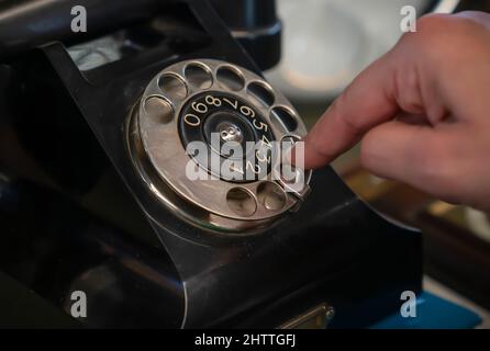 Altes schwarzes Drehtelefon mit weiblichen Fingern. Stockfoto