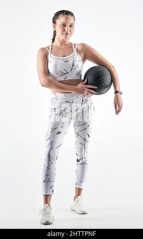 Ich möchte wie eine Actionfigur aussehen, nicht wie eine Puppe. Studioportrait einer sportlichen jungen Frau, die einen Übungsball vor weißem Hintergrund hält. Stockfoto