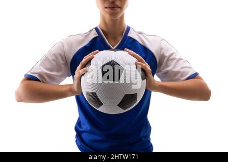 Mittelteil einer jungen Biracial-Fußballspielerin, die den Fußball vor weißem Hintergrund hält Stockfoto