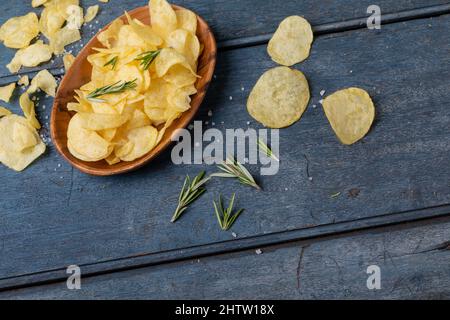 Blick aus der Perspektive auf Kartoffelchips in einer Schüssel mit Rosmarin und Salz auf einem Holztisch Stockfoto