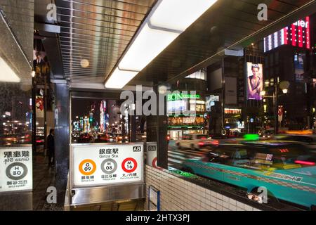 Taxis fahren an einem regnerischen Abend in Ginza, Tokio, Japan, vorbei an einem U-Bahn-Eingang Stockfoto