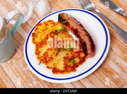 Das Nationalgericht der weißrussischen Küche ist draniki mit gebratenen Würstchen Stockfoto