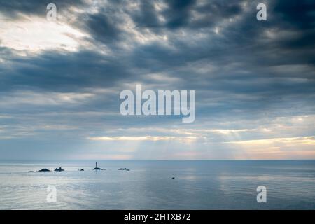 Vom berühmten westlichsten Wahrzeichen Großbritanniens und der Küste Cornis aus gesehen, ist das Longships Lighthouse umgeben von einem ruhigen Atlantischen Ozean im Sommer, eine dünne Schicht Stockfoto