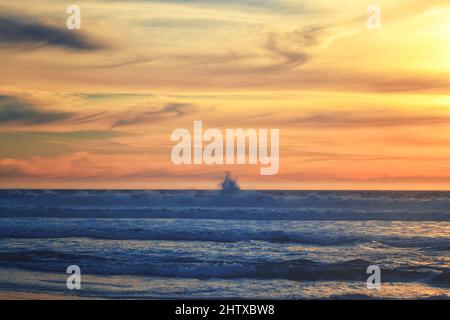 Sonnenuntergang am tropischen Strand. Leerer Sandstrand, riesige Wellen und wunderschöner wolkiger Himmel im Hintergrund Stockfoto