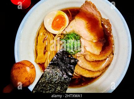 Suppenschüssel mit japanischen Shoyu-Ramen-Nudeln mit Ei und Schweinefleisch in einer Sojabrühe Stockfoto