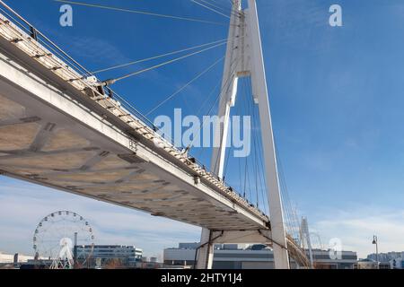 Moderne Fußgängerbrücke gegen den blauen Himmel. Ansicht von unten. Stockfoto