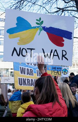 Protesterin mit Protestplakat gegen die russische Invasion in der Ukraine, zwei Friedenstauben in den nationalen Farben der Ukraine und Russlands Stockfoto