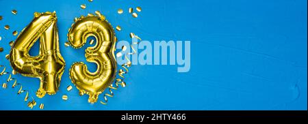 goldene Folienballon Zahl dreiundvierzig. Geburtstags- oder Jubiläumskarte mit der Aufschrift 43. Blauer Betonhintergrund. Jubiläumsfeier. Banne Stockfoto