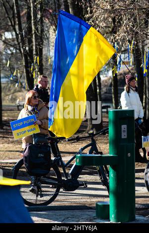 Mädchen während einer friedlichen Demonstration gegen den Krieg, Putin und Russland zur Unterstützung der Ukraine, mit Plakat zeigt Putin als Verbrecher und Flaggen Stockfoto
