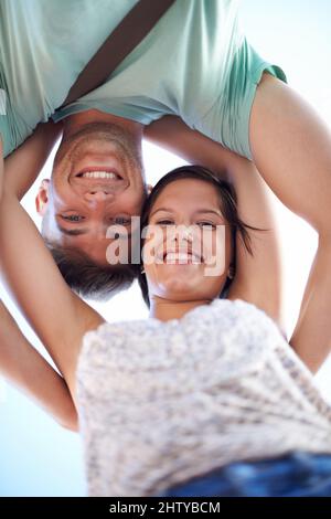 Hallo. Beschnittene Ansicht eines jungen Paares, das lächelt, während es auf die Kamera herunterschaut. Stockfoto