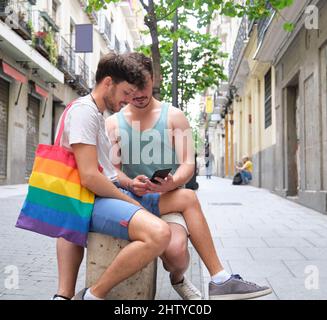 Schwule Paare, die das Smartphone auf der Straße benutzen. Stockfoto