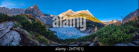 Panorama-Luftaufnahme des gefrorenen Sorapiss-Sees, umgeben von bunten Lärchen und Pinien und Dolomiten-Bergen im Herbst. Stockfoto