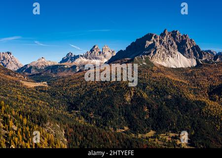 Die Felsformationen Cadini di Misurina und Tre Cime di Lavaredo, vom See Sorapiss aus gesehen, umgeben von bunten Lärchen und Pinien im Herbst. Stockfoto