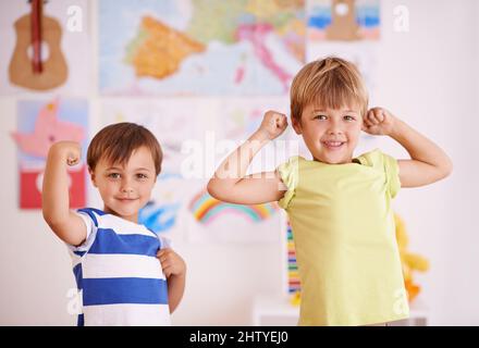 Er möchte genau wie sein großer Bruder sein. Zwei junge Jungen, die ihre Muskeln beugen, während sie im Schlafzimmer stehen. Stockfoto