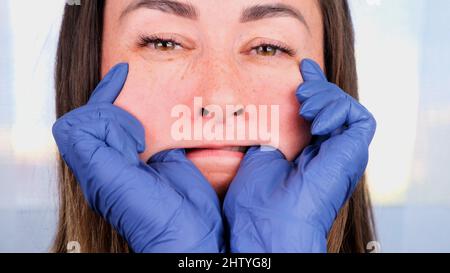 Die Ärztin Kosmetologin gibt sich eine Gesichtsmassage im Bukkal, lehrt und zeigt eine orale neuromuskuläre Intra-Massage aus nächster Nähe Stockfoto