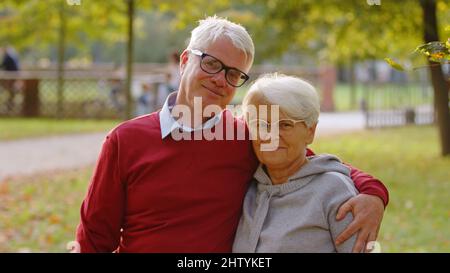 Porträt von zwei glücklichen älteren Erwachsenen im Park. Verheiratetes Rentnerpaar, das zur Kamera schaute und lächelte. Hochwertige Fotos Stockfoto