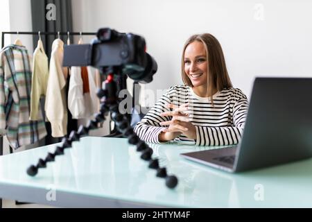 Selbstbewusste junge Vloggerin sitzt am Schreibtisch und dreht Live-Übertragungen mit professioneller Kamera, erfolgreiche Millennial-Girl-Sprecherin oder Coach sprechen reco Stockfoto