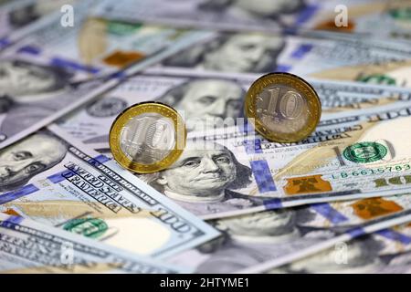 Russische Rubel-Münzen auf dem Hintergrund von US-Dollar. Konzept des Wechselkurses, amerikanische Sanktionen gegen die Wirtschaft Russlands, fallender Rubel Stockfoto