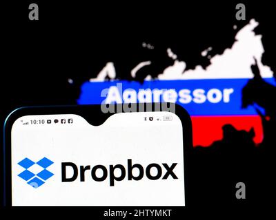 In dieser Abbildung wird das Dropbox-Logo auf einem Smartphone-Bildschirm mit einer russischen Flagge in Form einer Karte des Landes mit der Aufschrift Aggressor im Hintergrund angezeigt. Dropbox hat sich den Sanktionen gegen Russland angeschlossen. Stockfoto