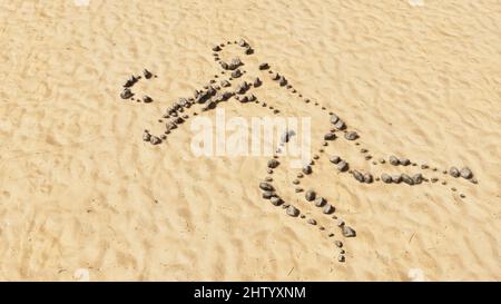 Konzept konzeptuelle Steine am Strand Sand handgemachte Symbolform, goldener sandiger Hintergrund, Volleyballspieler Schild. 3D Illustration Metapher für Sport, Co Stockfoto