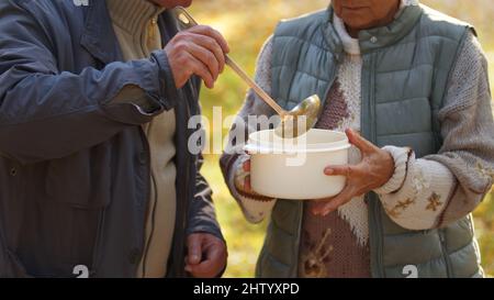 Zwei kaukasische Menschen teilen sich die Suppe miteinander. Konzept „Menschen in Not helfen“. Hochwertige Fotos Stockfoto