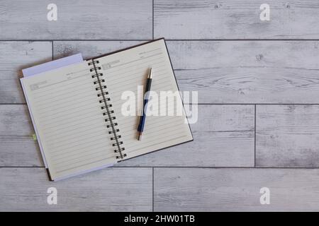 Öffnen Sie die Agenda und den Stift auf weißem Holzhintergrund Stockfoto
