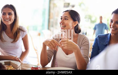 Gute Freunde, lustige Zeiten. Eine kurze Aufnahme einer Gruppe von Freunden, die zusammen Pizza genießen. Stockfoto