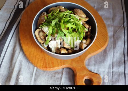 Warmer Pilzsalat mit Feta-Käse und Rucola auf einer Leinenserviette Stockfoto