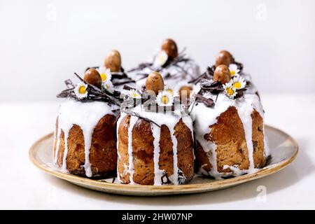 Hausgemachte traditionelle Ostern kulich Kuchen mit Schokolade Nester und Eier auf Keramikplatte über weißem Textur Hintergrund. Traditionelles ortodoxes osterrussi Stockfoto