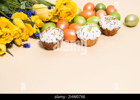 Osterkuchen, Eier und gelbe Tulpen auf beigem Hintergrund mit Platz für Text. Stockfoto