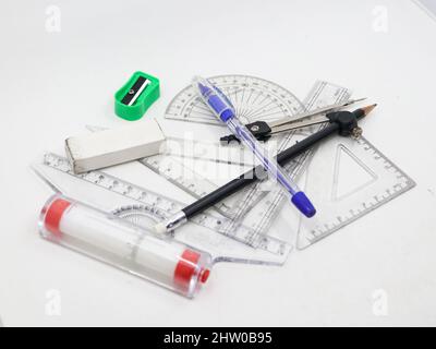 Geometrische Skizzierwerkzeuge wie Winkelmesser, Set Square, Lineal, Stift, Bleistift, Spitzer, Kompass und Radierer isoliert auf weißem Hintergrund Stockfoto