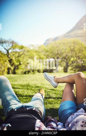 Das Leben ist voller schöner Momente. Eine kleine Aufnahme eines jungen Paares, das im Park auf dem Gras liegt. Stockfoto