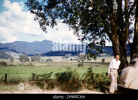 Young amen steht hinter dem Ford Prefect A493A Auto in der ländlichen Gegend von Victoria, Australien, 1956 nicht näher bezeichnete ländliche Lage Stockfoto