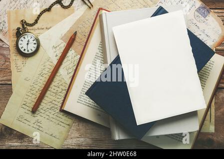 Weißes Schreibblatt mit Platz zum Kopieren auf Büchern und Postkarten neben einer alten Uhr und einem Bleistift Stockfoto