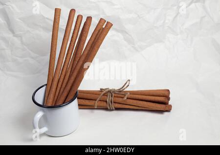 Roggen-Brotstangen grissini in der emaillierten Tasse und neben mit dem Seil auf dem Hintergrund des zerknitterten Papiers gebunden Stockfoto