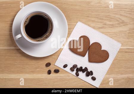 Herzförmige Ingwerkekse und Tasse Kaffee auf Holzhintergrund, Draufsicht Stockfoto