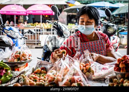 Bangkok, Thailand. 04. März 2022. Ein Erdbeerverkäufer inspiziert ihre Produkte auf dem Wongwian Yai Markt in Bangkok. Thailand öffnet sich vollständig geimpften internationalen Touristen wieder, indem es die Einschränkungen für „Test and Go“, das Quarantäneprogramm, lockere. Kredit: SOPA Images Limited/Alamy Live Nachrichten Stockfoto