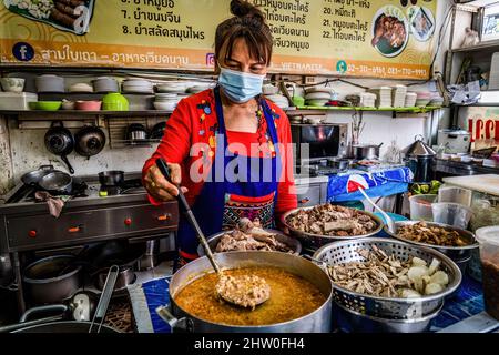 Bangkok, Thailand. 04. März 2022. Eine maskierte Verkäuferin wird an ihrem Street-Food-Stand in Bangkok gesehen, wie sie Thai-Chicken macht. Thailand öffnet sich vollständig geimpften internationalen Touristen wieder, indem es die Einschränkungen für „Test and Go“, das Quarantäneprogramm, lockere. Kredit: SOPA Images Limited/Alamy Live Nachrichten Stockfoto