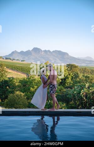 Ein Paar Männer und Frauen im Schwimmbad mit Blick auf die Weinberge und Berge von Stellenbosch Südafrika. Stockfoto